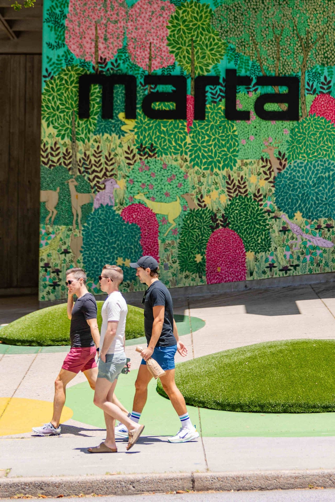 3 men walking with the MARTA subway sign in the background