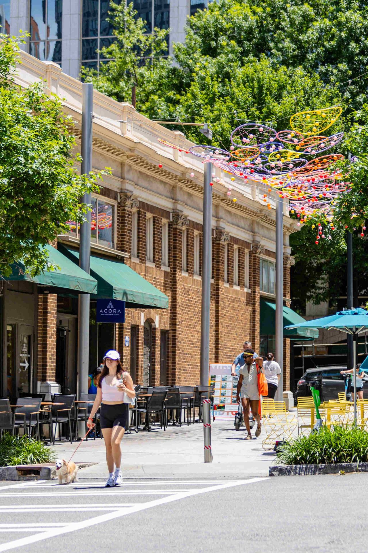 Street near Emmi Midtown featuring people walking & a woman walking her dog